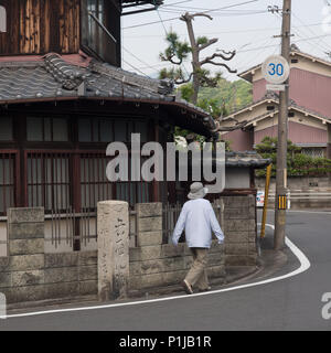 Femme marche autour de coin de rue, avec le doigt, route de poste guide, aucun pèlerin henro michi sentier, Shikoku 88 Pilgrim temple trail, Ehime, au Japon Banque D'Images