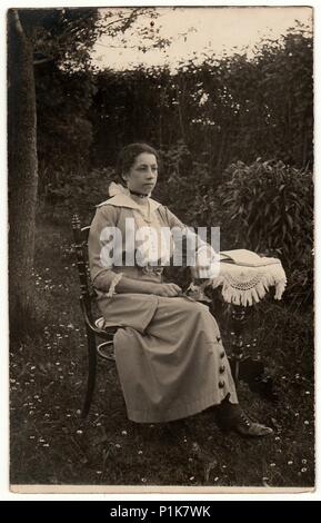 LA RÉPUBLIQUE TCHÉCOSLOVAQUE - VERS 1930s: Des photos d'époque montrent que la femme est assise sur une chaise historique à la petite table du jardin. Photographie d'antiquités en noir et blanc. 1930s Banque D'Images