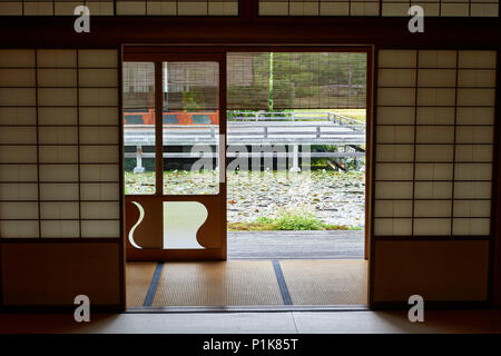 Vue sur un étang et un salon de thé traditionnel japonais par shoji porte. Banque D'Images