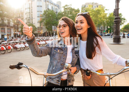 Image de deux jeunes amis de belles femmes à l'extérieur sur des vélos sur la rue. Banque D'Images