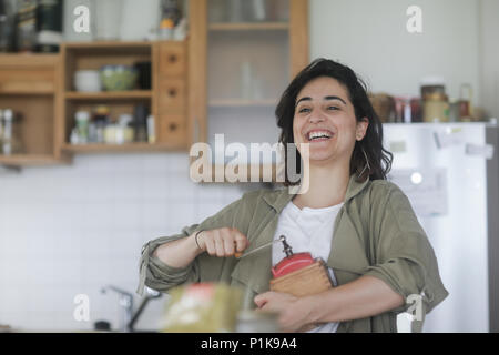 Smiling Woman standing dans la cuisine à l'aide d'un vieux moulin à café Banque D'Images