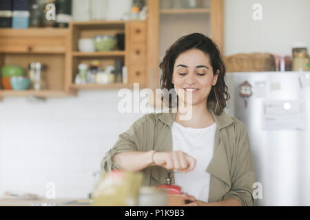 Femme debout dans la cuisine à l'aide d'un vieux moulin à café Banque D'Images