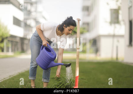 Femme debout dans une usine d'arrosage de jardin Banque D'Images