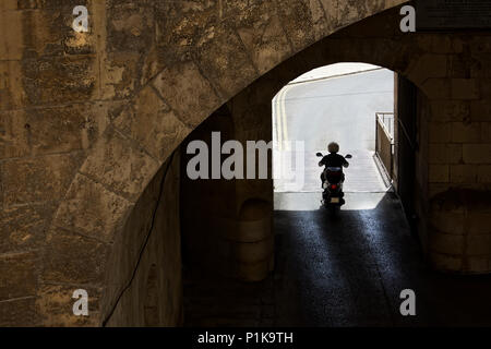 Man riding moto à travers un tunnel, Victoria gates, La Valette, Malte Banque D'Images