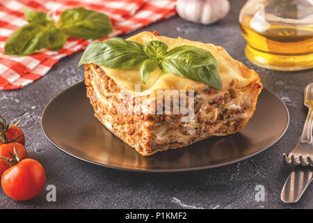 Lasagne traditionnelle faite avec du bœuf haché sauce bolognaise et béchamel garnie de feuilles de basilic. Banque D'Images