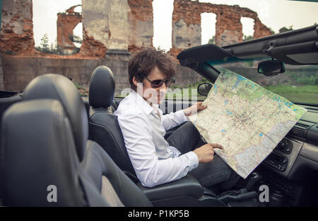 Beau jeune homme est titulaire d'une carte de route dans une voiture. Voyages et aventures concept. Tonique photo