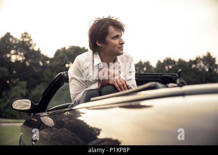 Beau jeune homme assis dans une voiture. Voyages et aventures concept. Tonique photo
