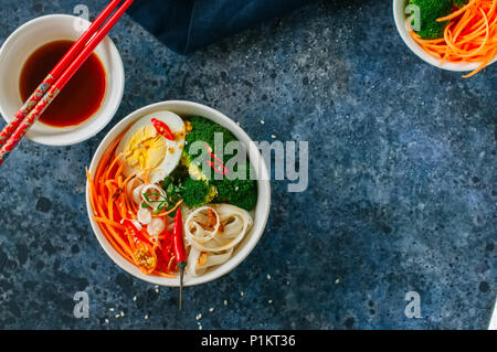 Concept d'aliments asiatiques. Bol de nouilles Udon avec des oeufs, épicé carotte, brocoli, graines de sésame. Vue d'en haut. Mise à plat. Banque D'Images