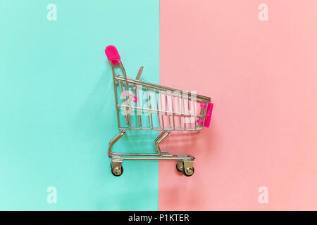 Petite épicerie supermarché push cart pour le shopping jouet avec roues et éléments en plastique rose sur rose et bleu pastel sur papier couleur télévision géométrique jeter Banque D'Images