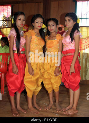 Quatre belles filles à un mariage cambodgien portant des fleurs dans leurs cheveux et vêtu de robes traditionnelles attendre pour jouer leur rôle dans la cérémonie. Banque D'Images