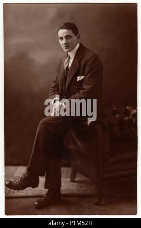 BARMBEK, ALLEMAGNE - circa 1930 : Vintage photo montre jeune homme porte costume et est assis sur le canapé. Photographie avec effet sépia. Banque D'Images