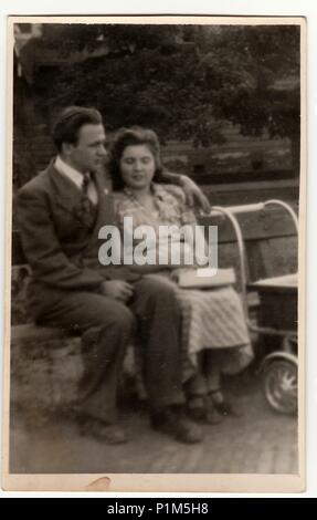 Italie - Vers les années 1940 : Vintage photo montre un jeune couple avec landau. Couple est assis sur un banc dans le parc de la ville. Antique phtography noir & blanc. Banque D'Images