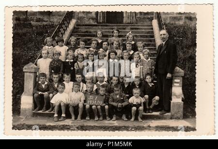 La République tchécoslovaque - 1939 : Vintage photo montre les élèves (camarades de classe) et leur enseignant posent devant l'école. La photographie ancienne en noir et blanc. Banque D'Images