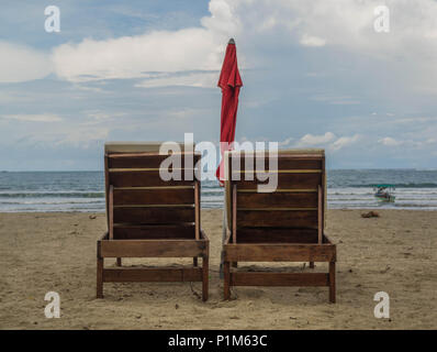 Deux chaises de plage-deux chaises de salon en bois sur la plage, avec un parapluie rouge, face à l'océan, à Playa Samara, Costa Rica Banque D'Images