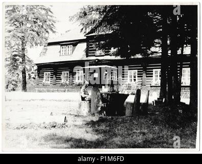 La République socialiste tchécoslovaque - circa 1960 : Retro photo montre cabane en bois sur l'arrière-plan. Deux personnes s'asseoir en face de maison en bois. Photographie noir et blanc vintage Banque D'Images
