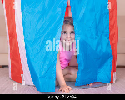 Portrait of cute girl joue à se cacher dans une tente jouet coloré. Focus sélectif et petite profondeur de champ. Banque D'Images