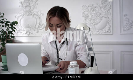 Femme médecin assis à table et l'écriture prescription sur formulaire spécial. Banque D'Images