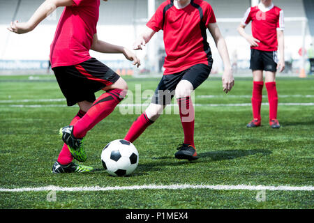 Méconnaissable garçons jouant au football dans domaine Banque D'Images
