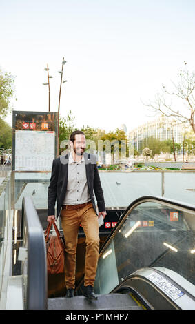 Longueur totale de l'image des profils business man dans l'usure formelle élégante en montant les escaliers du métro sur l'escalator en centre-ville avec des hommes en cuir sac et newspap Banque D'Images