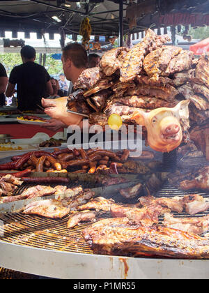 Cuisson cuire les côtes levées de porc et autres viandes des coupes sur un barbecue au charbon de bois dans un décrochage d'une foire de l'alimentation de rue. Banque D'Images