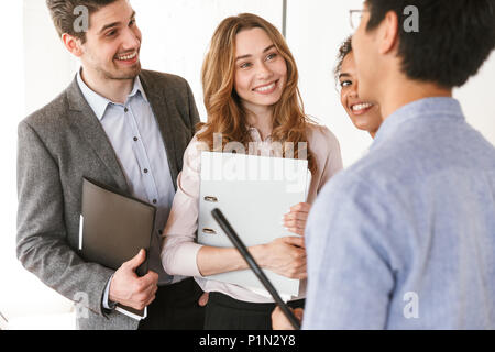 Groupe de young businesspeople standing multiethnique dans un bureau et de rire Banque D'Images