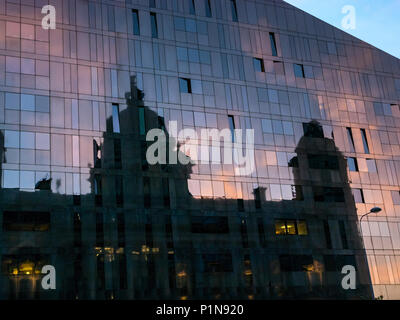 Front de mer de Liverpool, Liverpool, Angleterre, Royaume-Uni, le 12 juin 2018. Météo France : coucher de soleil sur les quais à Liverpool. Un édifice moderne en verre avec un reflet de l'historique Royal Liverpool building lit up at Dusk fait un contraste frappant avec la faible lumière au crépuscule Banque D'Images