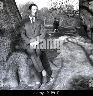 Années 1950, historiques, printemps et habillés d'un homme appuyé contre un arbre dans le parc de Richmond, Richmond, Surrey, Angleterre, Banque D'Images