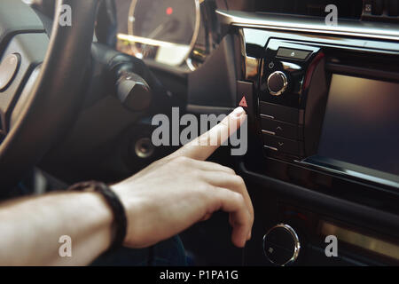 Homme est assis dans la voiture et pousser sur le bouton d'urgence rouge Banque D'Images