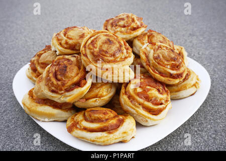 Boulangerie maison mini boulettes pizzete, snack-pizza, faite de pasty, fromage et jambon, sur la plaque blanche. De savoureux en-cas frais Banque D'Images