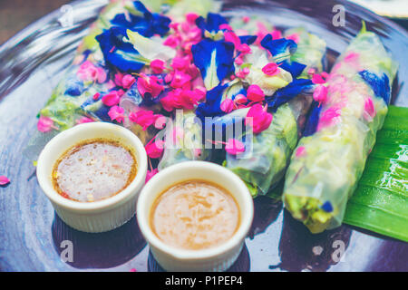 Petits pains frais avec les nouilles de riz enveloppés dans du papier de riz et salade thaï avec des herbes, de concombre, de carottes marinées et de fleurs de banane avec sauce aux arachides avec j Banque D'Images