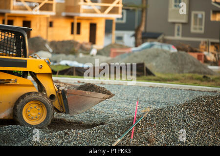 Petit chargeur avant déménagement et plaçant de gravier dans un parc d'une nouvelle construction ; Langley, Colombie-Britannique, Canada Banque D'Images