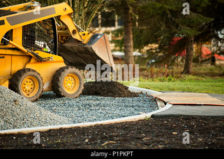 Petit chargeur avant déménagement et plaçant de gravier dans un parc d'une nouvelle construction ; Langley, Colombie-Britannique, Canada Banque D'Images