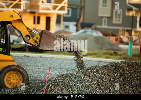 Petit chargeur avant déménagement et plaçant de gravier dans un parc d'une nouvelle construction ; Langley, Colombie-Britannique, Canada Banque D'Images