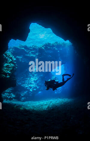 Scuba Diver nage à travers des arches de lave avec les rayons du soleil, site de plongée des cathédrales ; Lanai City, Lanai, Hawaii, United States of America Banque D'Images