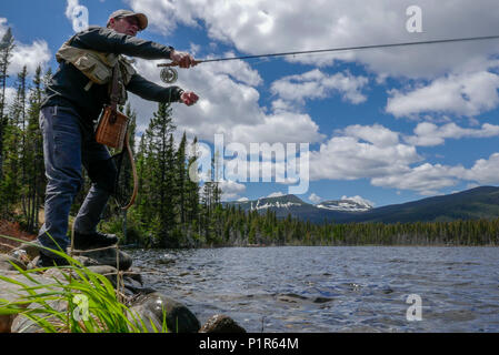 La pêche à la mouche sur les rives d'un lac de montagne vierge Banque D'Images