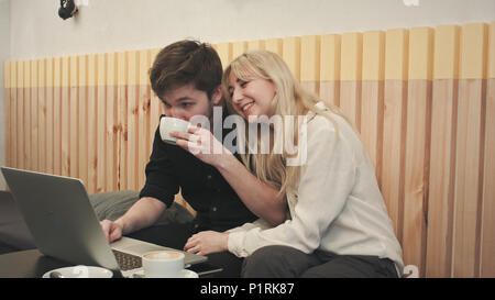 Couple d'étudiants ayant le chat vidéo avec des amis dans un café Banque D'Images