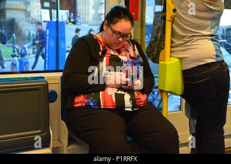 Un excès de poids, de taille plus femme assise et à l'aide de Phone Banque D'Images