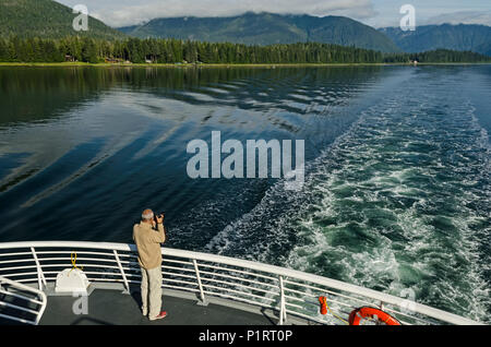 Tourist photographing Wrangell Narrows à North en direction de Pétersbourg à partir de la poupe de l'état de l'Alaska, le sud-est de l'Alaska Ferry Banque D'Images