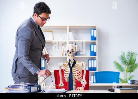 Businessman working avec squelette in office Banque D'Images