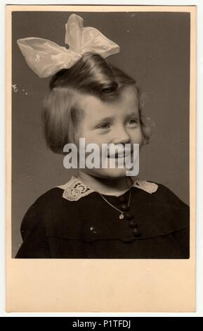 La République tchécoslovaque - circa 1950 : Vintage photo montre un portrait d'une petite fille mignonne avec ruban dans les cheveux. Retro noir et blanc de la photographie. Banque D'Images