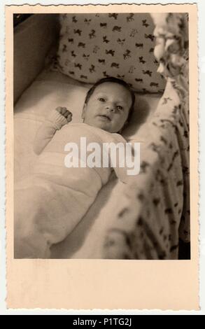 Allemagne - 1954 : Vintage photo montre mignon petit bébé dans un lit bébé (lit bébé, lit bébé). Retro noir et blanc de la photographie. Banque D'Images