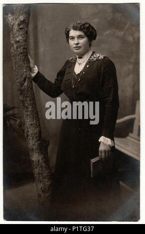 Allemagne - VERS 1920 : Vintage photo montre femme avec les cheveux courts. Femme est titulaire d'adresses. Retro noir et blanc photographie studio avec effet sépia. Banque D'Images