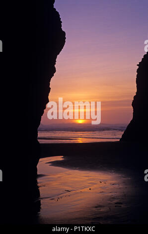 Cape Sebastian State Park le long de la côte sud de l'Oregon avec orange avec la lumière à travers des formations rocheuses qui se profile, à marée basse. Banque D'Images