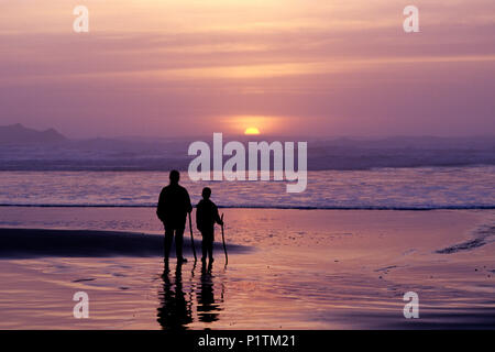 Cape Sebastian le long de la côte sud de l'Oregon, le long de la route 101 avec le coucher du soleil spectaculaire avec une jeune fille mère randonnées avec bâton de marche à marée basse. Banque D'Images