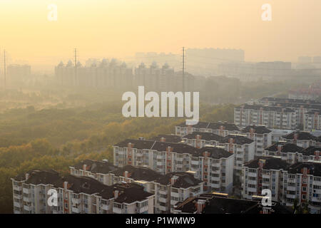 Le smog se combine avec brume matinale que soleil se lève sur les immeubles à appartements dans une banlieue de Shanghai Banque D'Images