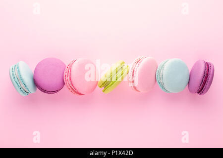 La ligne de macarons colorés sur fond rose. Vue d'en haut. Banque D'Images