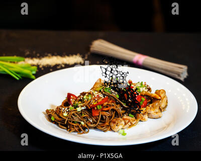 Nouilles de sarrasin Soba, oignon, carotte, poivron, bulgare, cuisses de poulet, hot chili peppers sauce Chili, l'oignon vert. Banque D'Images