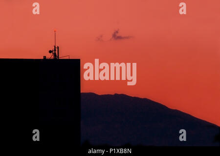 Immeuble avec antenne et des lumières de sécurité sur Red sky Banque D'Images