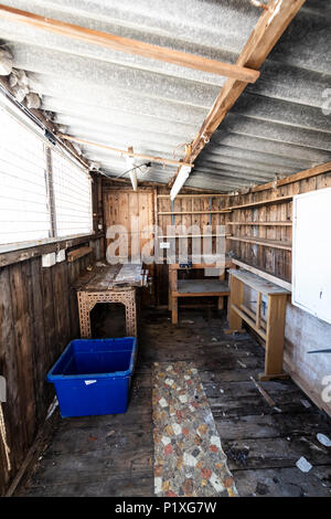 L'intérieur d'un vieux hangar abandonné avec des workbench, placards, étagères, toit de l'amiante et le dangereux. Banque D'Images