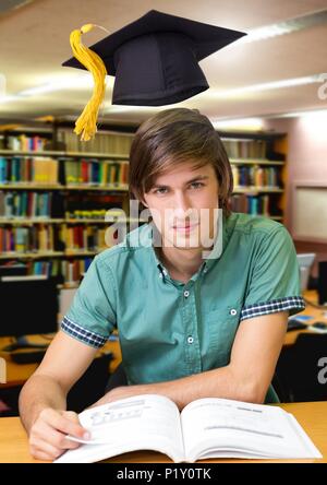 Homme d'étudiants dans le domaine de l'éducation bibliothèque avec graduation hat Banque D'Images